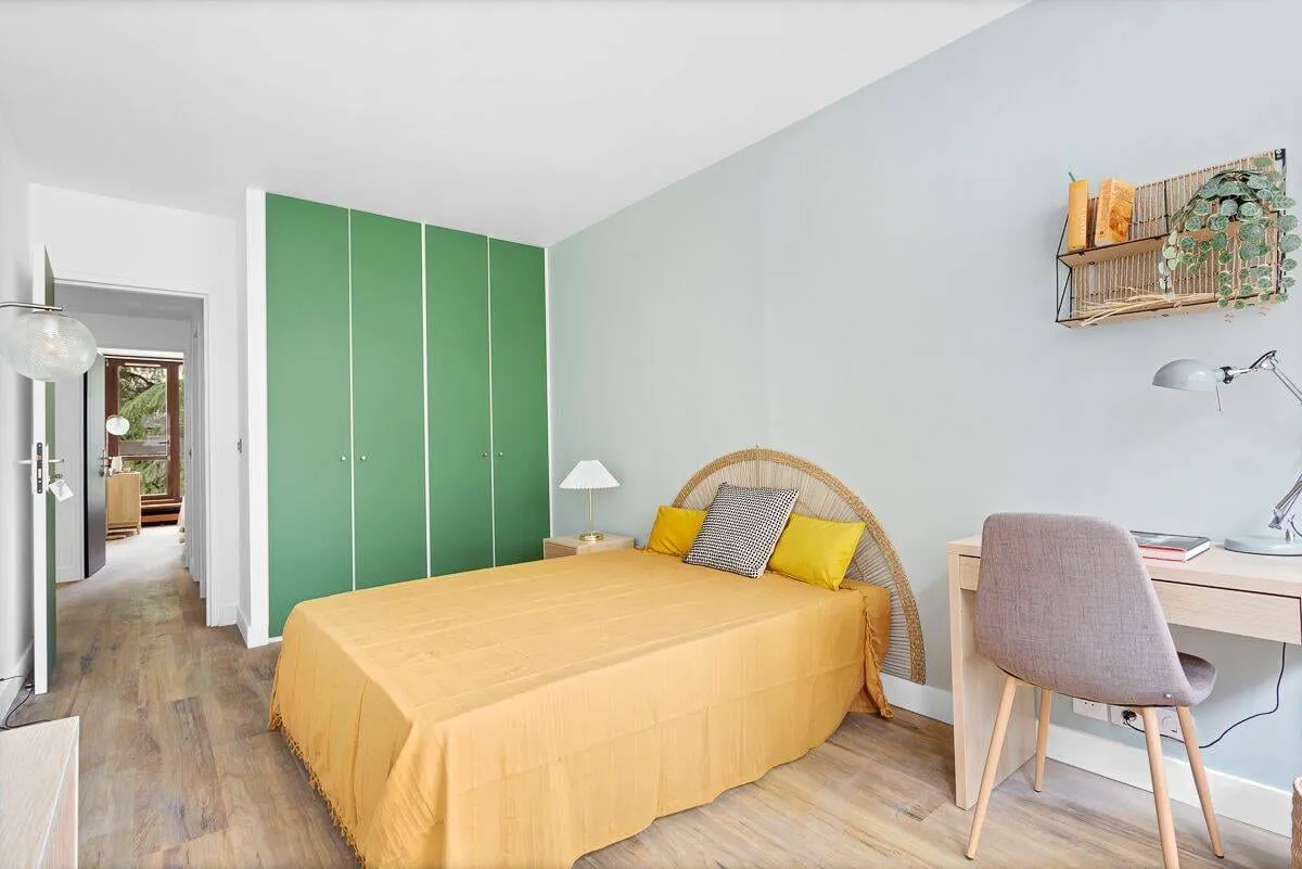 Chambre avec lit double, couvre-lit jaune et bureau
