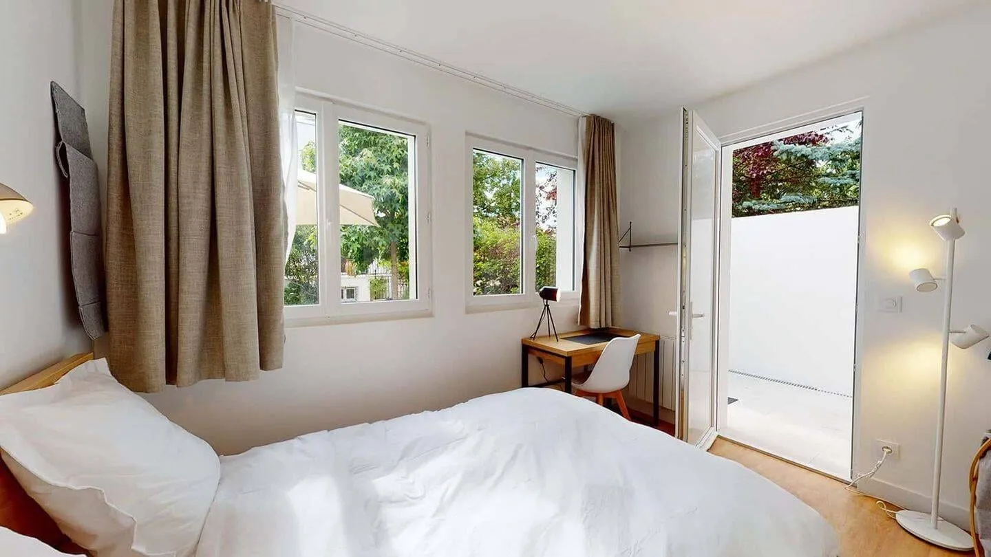 Chambre avec grandes fenêtres et rideaux
