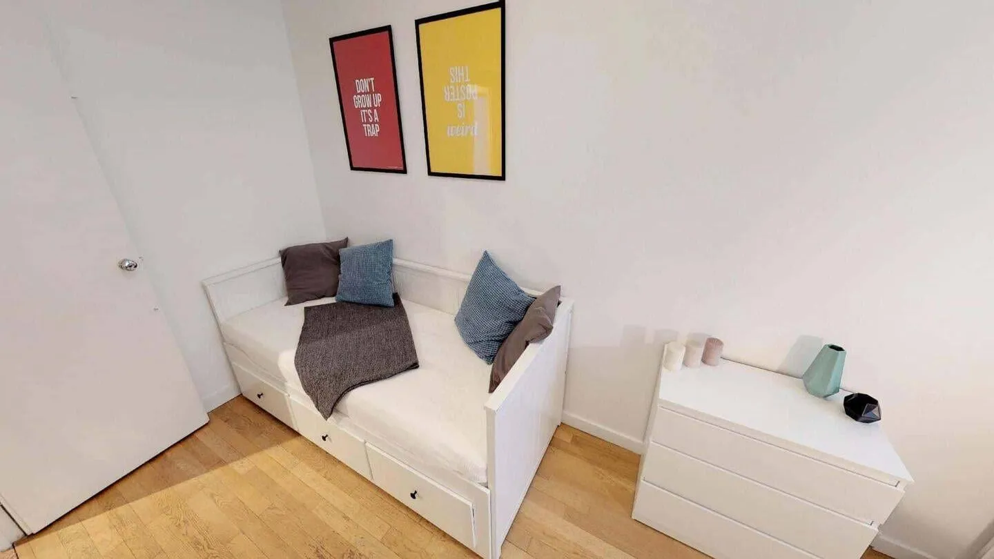Chambre meublée avec lit simple et affiches encadrées
