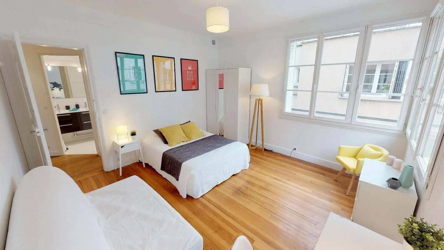 Chambre avec bureau devant deux fenêtres