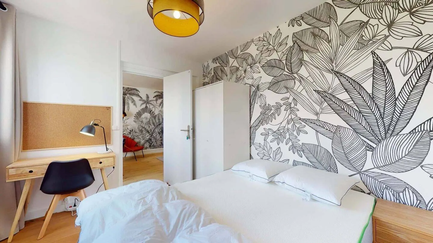 Chambre avec lit double et papier peint végétal