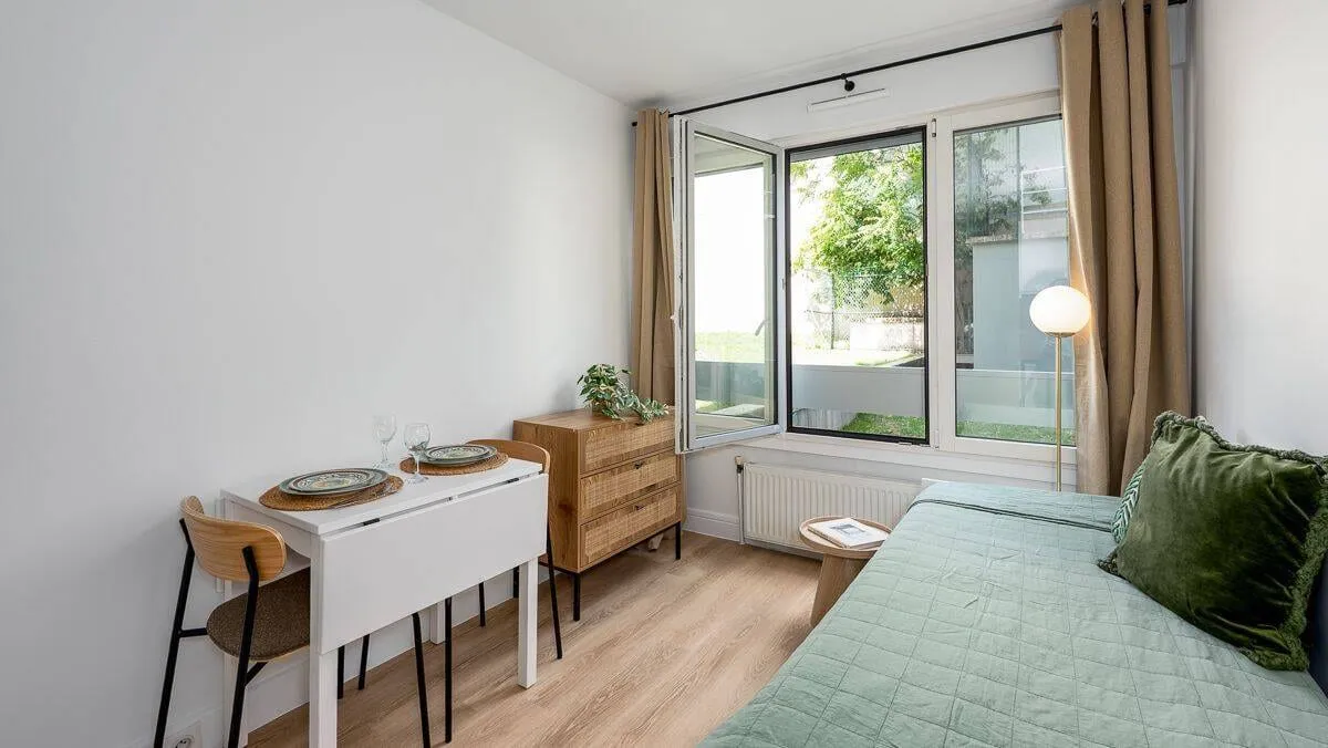Studio avec bureau, lit et fenêtre sur rue