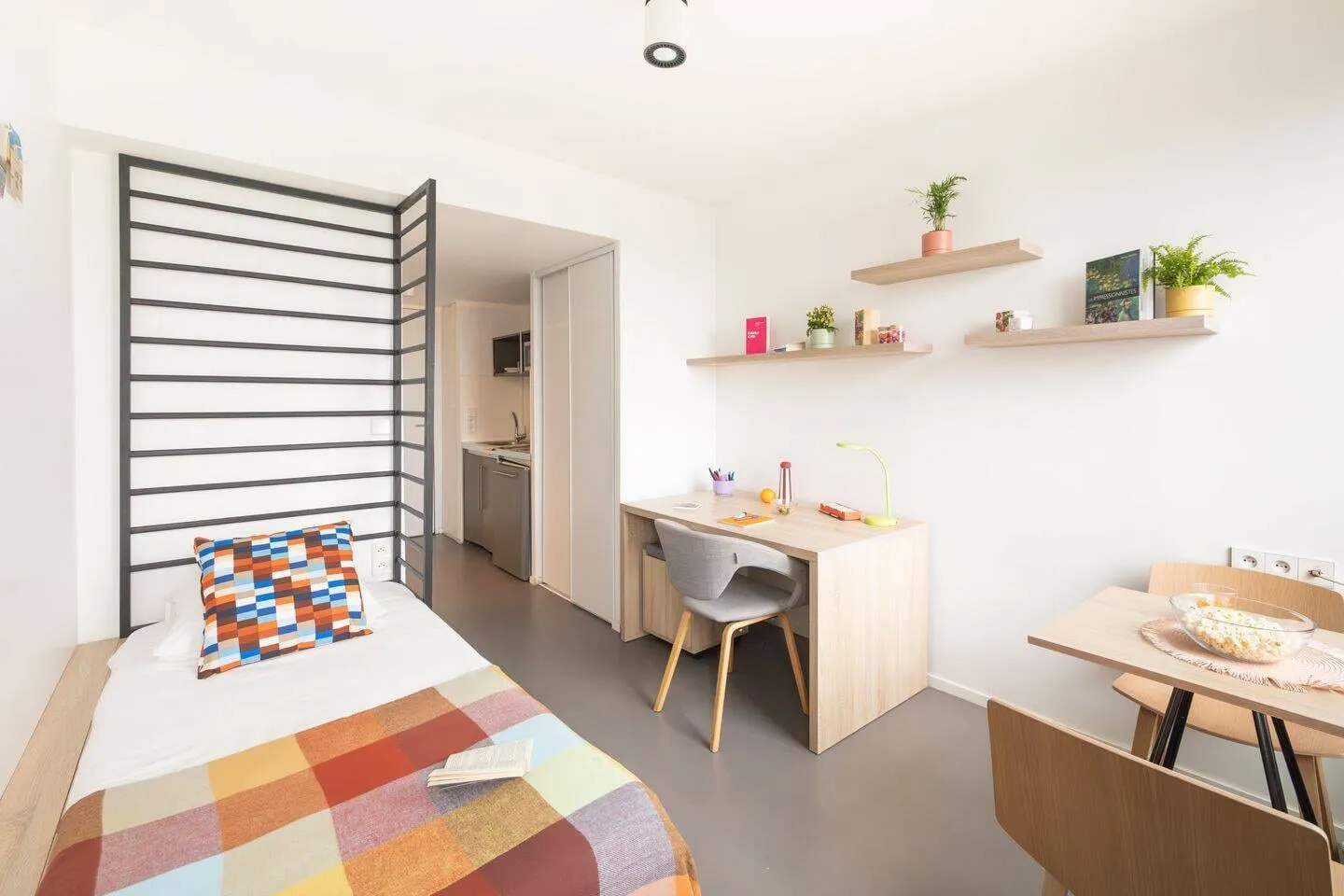 Studio avec bureau, étagères murales et lit simple