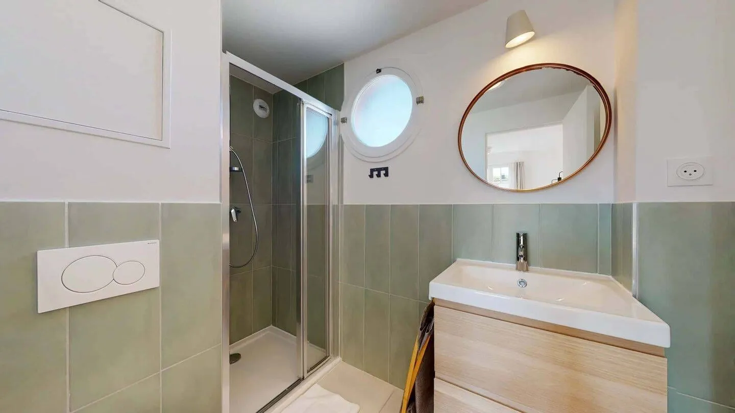 Salle d'eau avec douche et miroir rond