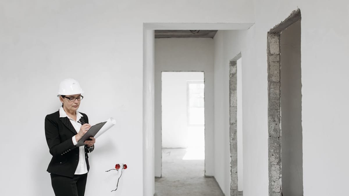 Diagnostiqueur muni d'un casque et d'un presse-papiers dans un logement vide